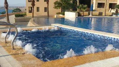a swimming pool with a fountain in the middle at Comfy Stays Sea View Apartments at DeadSea Samarah Resort in Sowayma