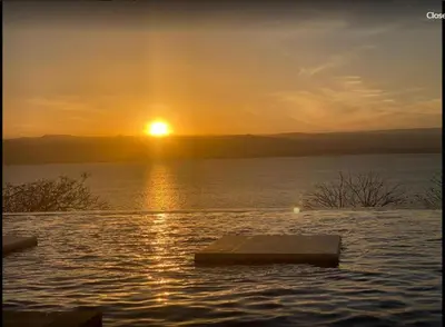 a sun setting over a large body of water at Comfy Stays Sea View Apartments at DeadSea Samarah Resort in Sowayma