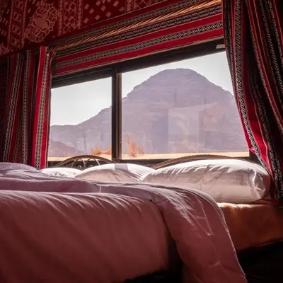 a bed with a view of a mountain through a window at Bedouin Yoga & Trekking Camp Wadi Rum in Wadi Rum