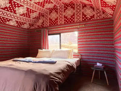 a bed in a room with a red and black wall at Bedouin Yoga & Trekking Camp Wadi Rum in Wadi Rum