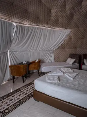 a room with two beds and a table with a desk at rum rema camp in Wadi Rum