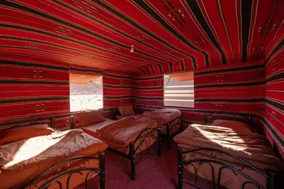 a red room with four beds and a window at Wadi Rum Trail in Wadi Rum