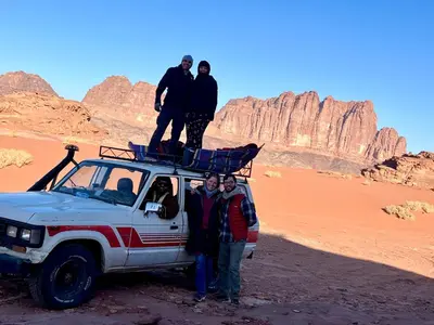 a group of people standing on the roof of a vehicle in the desert at Wadi Rum Trail in Wadi Rum