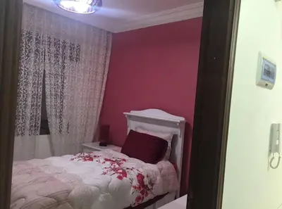 a bedroom with pink walls and a white bed with flowers at Modern Brand New Apartment in Amman