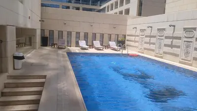 a large swimming pool in a building with chairs at Amazing Studio in DAMAC in Amman