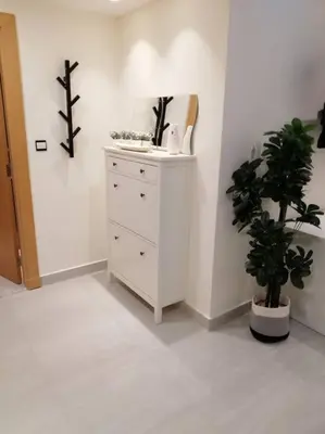 a white dresser in a room with a potted plant at Amazing Studio in DAMAC in Amman