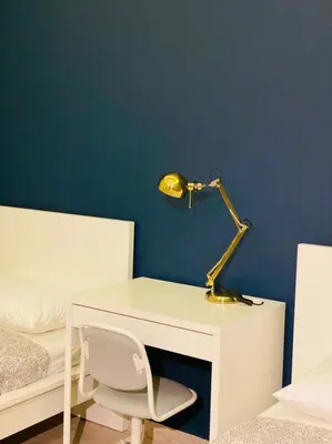 a desk with a lamp and a chair next to a bed at Elite Corner Apartment in Ţāb Kirā‘