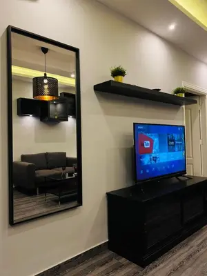 a living room with a mirror and a television at Elite Corner Apartment in Ţāb Kirā‘