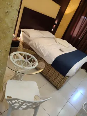 a bedroom with a bed and a chair and a table at Roza Beach Aqaba in Aqaba