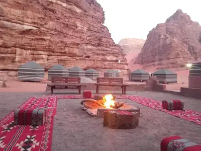 a camp with benches and a fire in the desert at Wadi Rum White Mountain Camp in Wadi Rum