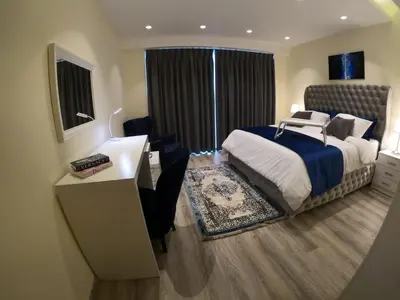 a bedroom with a bed and a desk and a window at Luxury Apartment in DAMAC Towers in Amman