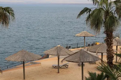 a group of umbrellas on a beach with the ocean at Samarah Dead Sea Resort Studio-CP6 Traveler Award 2026 Winner Thursday, Friday and Saturday Groups consisting solely of male guests are not permitted in Sowayma