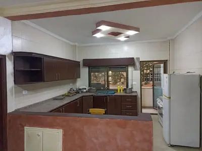 a kitchen with brown cabinets and a white refrigerator at Economic Apartment in Az Zarqa