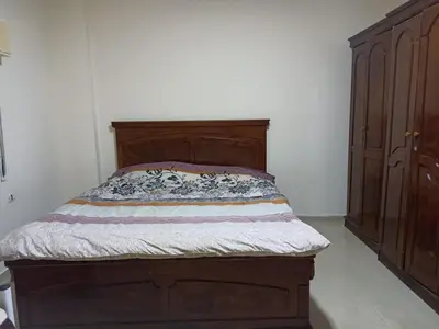 a bed in a bedroom with a wooden headboard at Economic Apartment in Az Zarqa