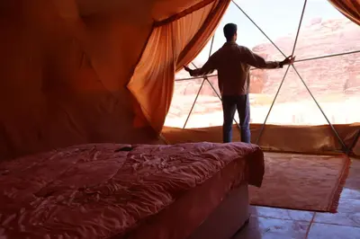 a man standing in a tent looking out the window at Wadi rum Bubble Camp & tour in Wadi Rum