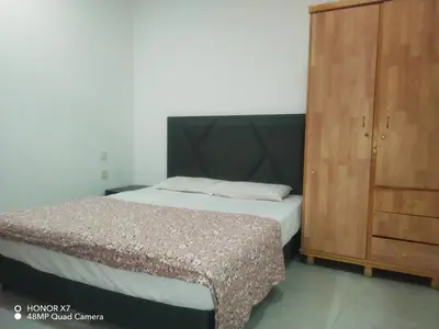 a bedroom with a bed and a wooden cabinet at Farah Plaza Hostel &Hotel Apartments in Aqaba