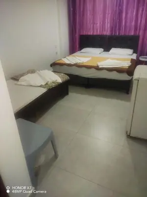 a room with two beds and a table and a chair at Farah Plaza Hostel &Hotel Apartments in Aqaba