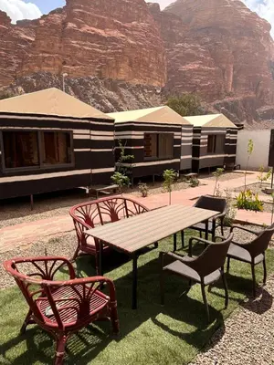 a picnic table and chairs in front of a building at Wadi Rum Oryx Hostel & Tours in Wadi Rum