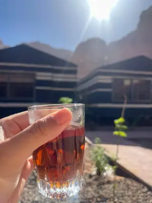 a person holding a glass of drink in their hand at Wadi Rum Oryx Hostel & Tours in Wadi Rum