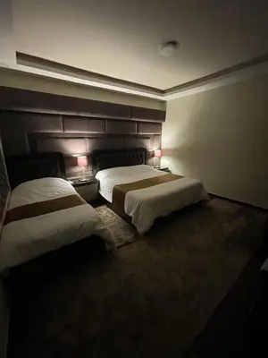 two beds in a hotel room with two lamps at Oqdeh studio in Jerash