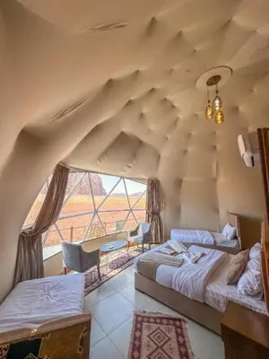 a room with two beds and a large window at Mountain Magic Camp Wadi Rum in Wadi Rum