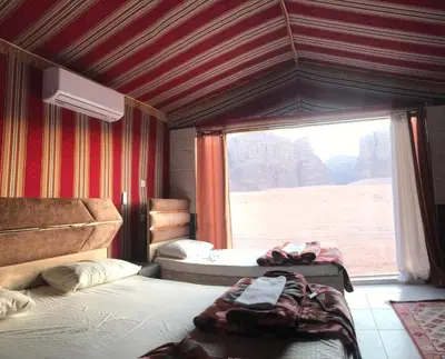 a room with two beds and a large window at Mountain Magic Camp Wadi Rum in Wadi Rum
