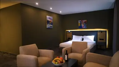 a hotel room with a bed and two chairs at Aitch Boutique Hotel - an LIH Hotel in Madaba