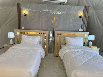 two beds sitting next to each other in a bedroom at Qimam Al Sarab Camp Wadi Rum in Wadi Rum