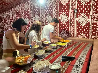 a group of people standing around a table with food at Bedouin Memories Camp in Wadi Rum
