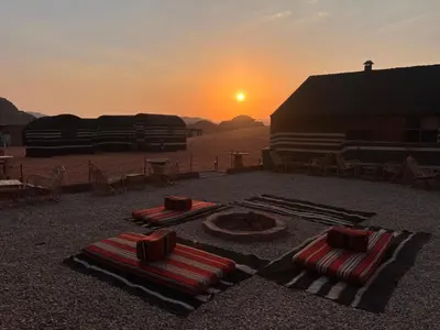 two beach towels on the ground with the sunset in the background at Wadi Rum Trip Bedouin Camp in Wadi Rum