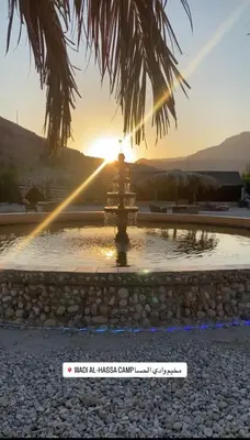 a fountain with the sunset in the background at Wadi Al-Hassa camp in Khawkhah