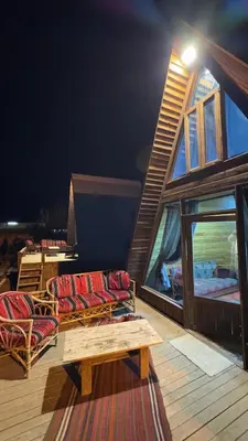 a house with two chairs and a table on a deck at Wadi Al-Hassa camp in Khawkhah