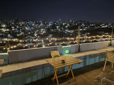 a table and chairs on a rooftop at night at Rainbow Guest House in Amman