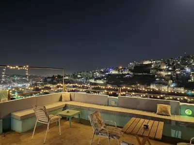 a balcony with a table and chairs at night at Rainbow Guest House in Amman