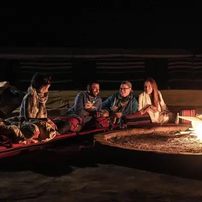 a group of people sitting next to a fire at stars magic camp in Wadi Rum