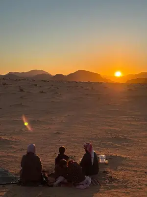 a group of people sitting in the desert watching the sunset at stars magic camp in Wadi Rum