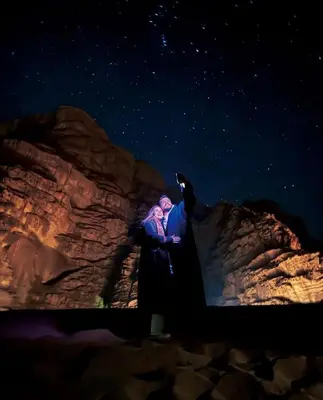 two people sitting on a rock under a starry sky at stars magic camp in Wadi Rum