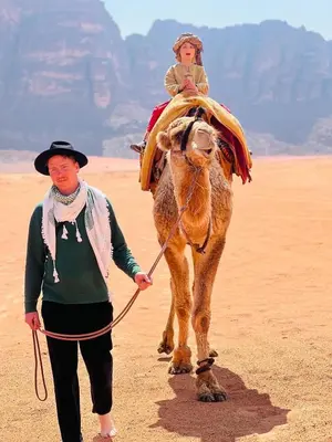 a woman leading a camel in the desert at stars magic camp in Wadi Rum