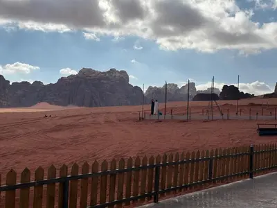 a man standing in a desert with mountains in the background at falling Stars Camp in Wadi Rum