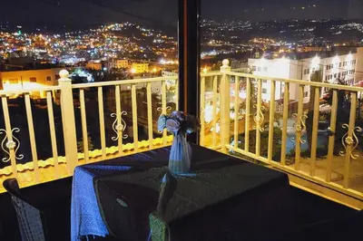 a table sitting on top of a balcony at night at atoom lodge in Jerash