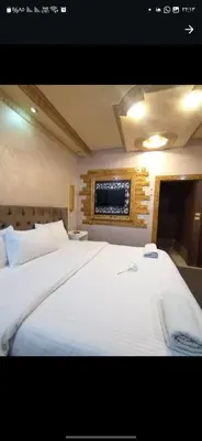 a bedroom with a large white bed with a tv on the wall at Hadrian's Arch in Jerash