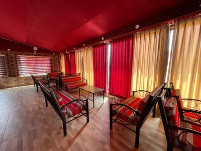 a row of chairs and tables in a room with red curtains at Rum Magic Nights in Wadi Rum