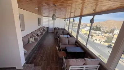 a restaurant with couches and tables and a large window at Beit Alshabaan Inn in Wadi Musa