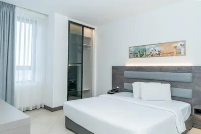 a white bedroom with a bed and a window at Liv Weibdeh Hotel Suites in Amman