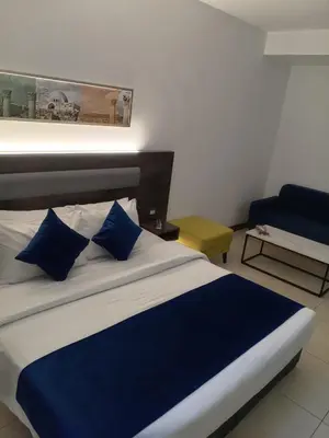 a bed with blue pillows in a room at Liv Weibdeh Hotel Suites in Amman