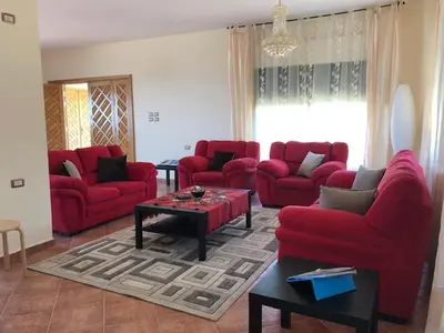 a living room with red couches and a coffee table at Charming House in Amman + Balcony in Amman