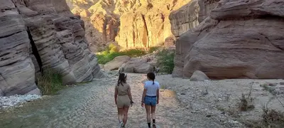 two people walking down a river in a canyon at Safi Kitchen Hostel in Aş Şāfī