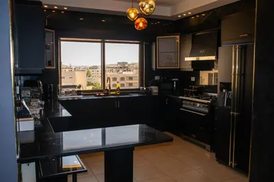 a kitchen with black cabinets and a large window at Alghalayieny Modern Apartments in Amman