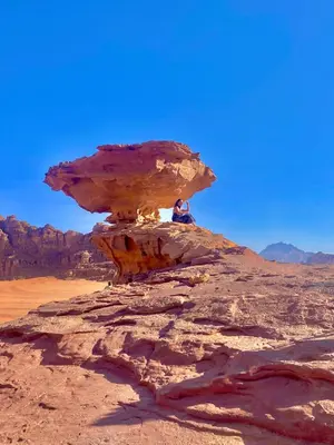 a person sitting on a rock in the desert at Katrina Rum camp in Wadi Rum