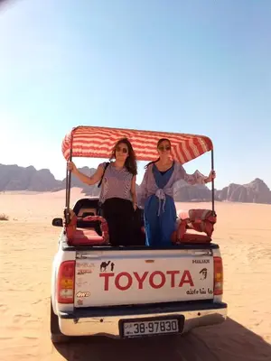 a man and woman sitting in the back of a truck in the desert at Katrina Rum camp in Wadi Rum